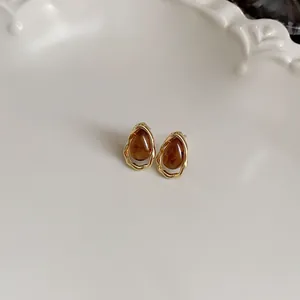 Macro view of vintage brown teardrop stud earrings with irregular gold-tone borders