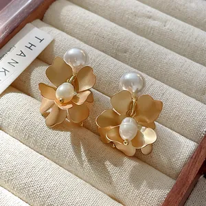 Close-up of elegant gold flower earrings with white pearls in a jewelry tray