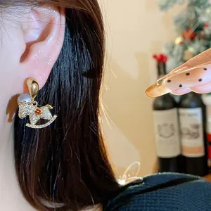 Detailed view of elegant gold rocking horse earrings with zircon and pearl accents on model