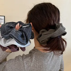 Detailed view of large vintage striped fabric scrunchies on hair and held in hand