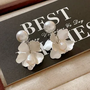 Detailed view of elegant white flower earrings with freshwater pearls on a display card