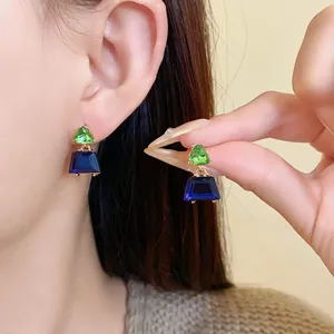 Detailansicht der geometrischen Trapezohrringe mit grünen Dreiecken und blauen Kristallen