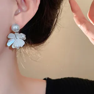 Detailed close-up view of elegant white flower earring with freshwater pearls on ear