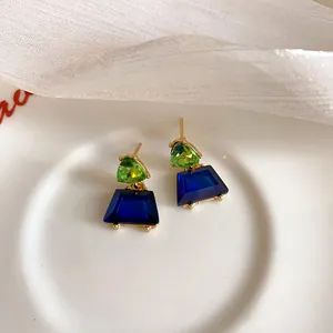 Nahaufnahme der geometrischen Trapez-Ohrstecker mit grünen und blauen Kristallen