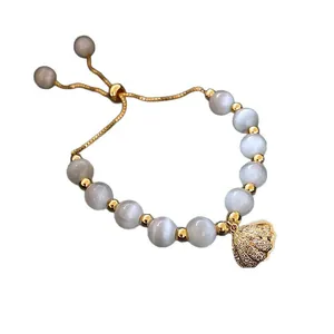 Elegante bracciale di perle occhio di tigre con ciondolo a conchiglia dorata lucida.