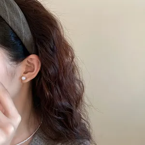 Detailed side view of a minimalist brown striped fabric headband on an Asian model