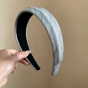 Detailed macro view of a grey herringbone fabric wide headband being held by a hand