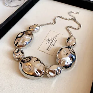 Detailed view of a silver irregular geometric metal necklace on a professional display tray