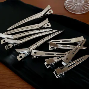 Detailed macro shot of silver minimalist metal duckbill hair clips displayed on tray