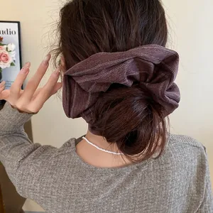 Detailed view of a large brown striped fabric scrunchie elegantly styled on a bun