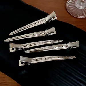 Detailed view of silver metal geometric duckbill hair clips with hole pattern