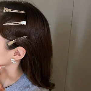 Close-up of minimalist metal duckbill hair clips and pearl floral earring on model