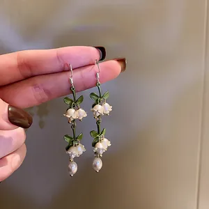 Hand-held close-up of elegant lily of the valley earrings with pearls for women