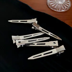 Detailed shot of minimalist silver metal duckbill hair clips on black velvet surface