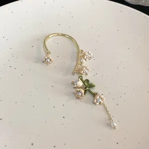 Detailed view of an elegant lily of the valley flower ear cuff with delicate pearls.