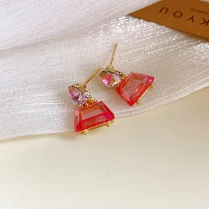 Detailansicht der rosa trapezförmigen geometrischen Ohrringe im Goldton-Design.