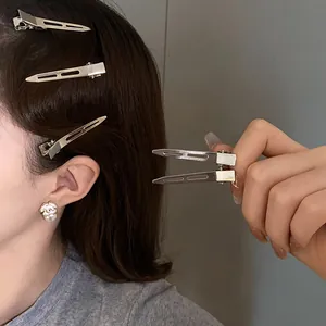 Detailed view of minimalist silver metal duckbill hair clips styled on side hair profile