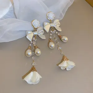 Detail of elegant pearl lily of the valley drop earrings with white rose and bow tassels
