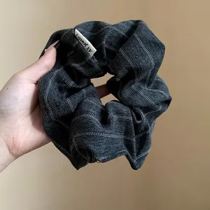 Detailed macro view of a dark grey striped fabric scrunchie with brand label