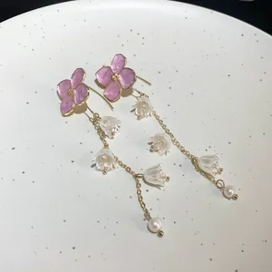Macro detail shot of elegant purple flower and white lily of the valley earrings with pearls