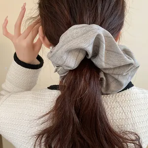 Detailed view of a grey herringbone striped oversized fabric scrunchie in long hair