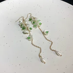 Close-up of pearl Lily of the Valley dangle earrings with green crystal accents