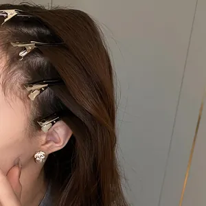 Close-up of metallic duckbill hair clips styled on side bangs with polished finish