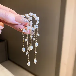 Close-up of pearl lily-of-the-valley ear hook earrings with elegant tassel design