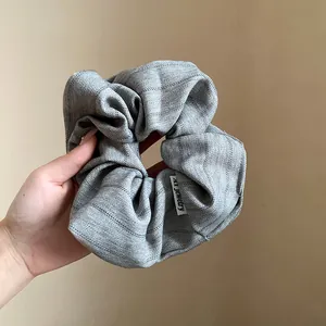 Close-up detail of a grey herringbone fabric scrunchie with elegant striped texture