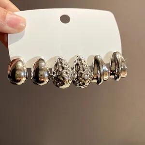 Vista dettagliata di un set di orecchini d'argento con design lisci e pieghettati.