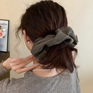 Close-up of a striped brown fabric scrunchie styling a low bun on an elegant woman
