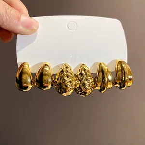 Dettaglio macro di tre paia di orecchini a goccia e plissettati placcati in oro.