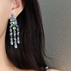 Detailed macro view of long dangling tassel earrings with blue and green oval zircon stones