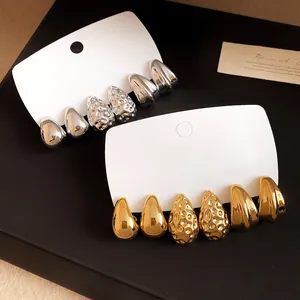 Primo piano di orecchini a goccia e a pieghe minimalisti in finitura oro e argento