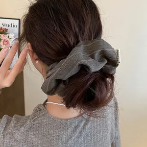 Detailed view of a retro striped fabric scrunchie hair tie styled in a bun hairstyle