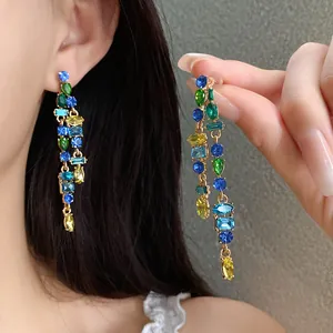 Macro view of elegant long gold tassel earrings featuring colorful vibrant zircons