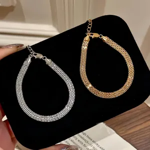 Gros plan détaillé de bracelets en maille plate plaqués or et argent sur velours noir.