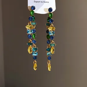 Detail of colorful rhinestone drop earrings with mixed-cut blue, green, and yellow gems.
