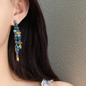 Close-up of elegant zircon tassel earrings with colorful stones on an Asian model