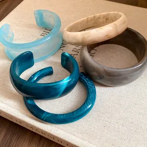 Detail view of various acrylic marbled bangles and open cuffs with retro smudge patterns