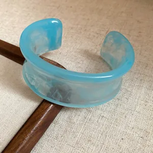 Detailed close-up showing the artistic marbled pattern of a blue acrylic open cuff bracelet