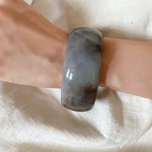 Close-up of a gray marbled acrylic bangle bracelet worn on a woman's wrist