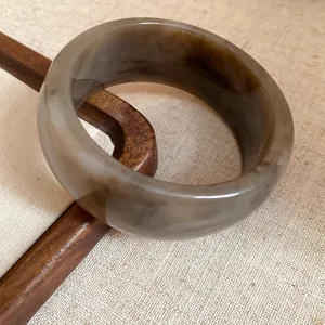 Close-up of vintage marbled grey and brown acrylic bangle on a wooden display stand
