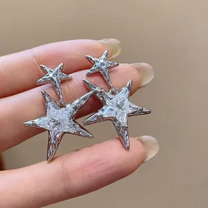 Sparkling zircon star drop earrings in silver finish held by hand to show detail