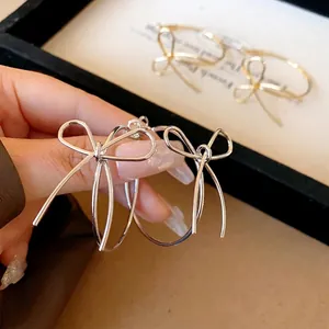 Elegant silver needle hoop earrings with bow design in silver and gold tones