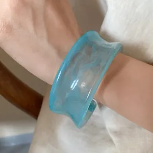 Detailed close-up showing the marbled texture of a light blue acrylic open cuff bracelet