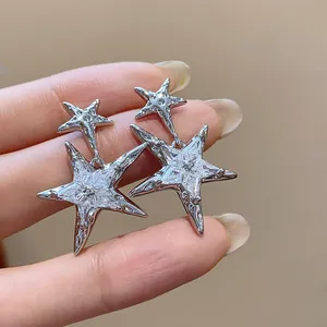 Close-up of sparkling zircon star-shaped silver needle earrings in a minimalist design