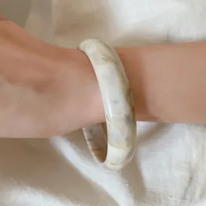 Close-up of a chic marbled acrylic bangle showing detailed natural texture on wrist