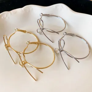 Detailed view of gold and silver minimalist bow-shaped hoop earrings on a ceramic plate