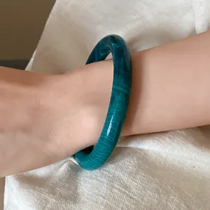 Close-up of green marbled acrylic bangle on wrist with vintage style